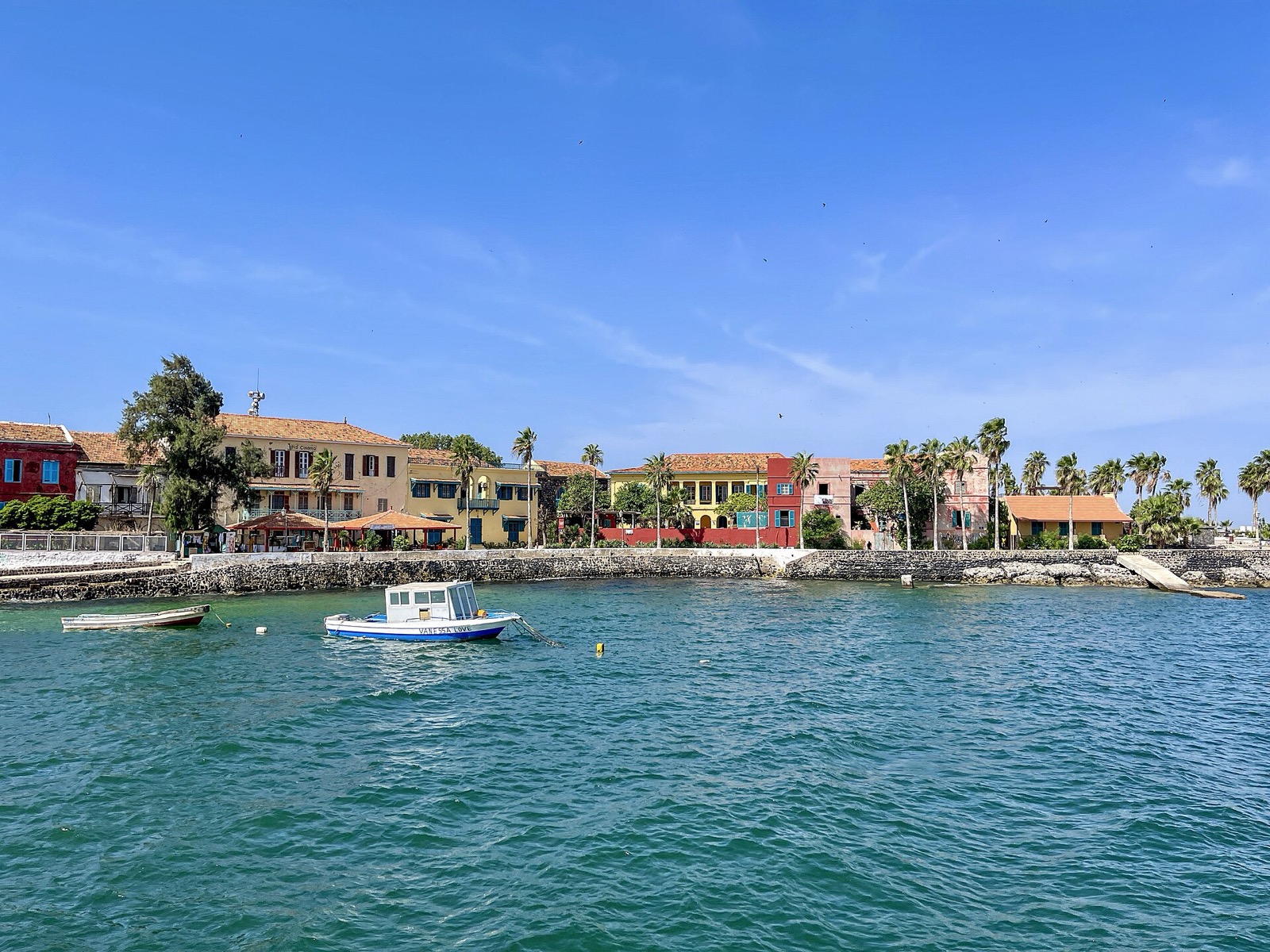 Casas de colores y barcas en el agua turquesa de la isla de Gorée.