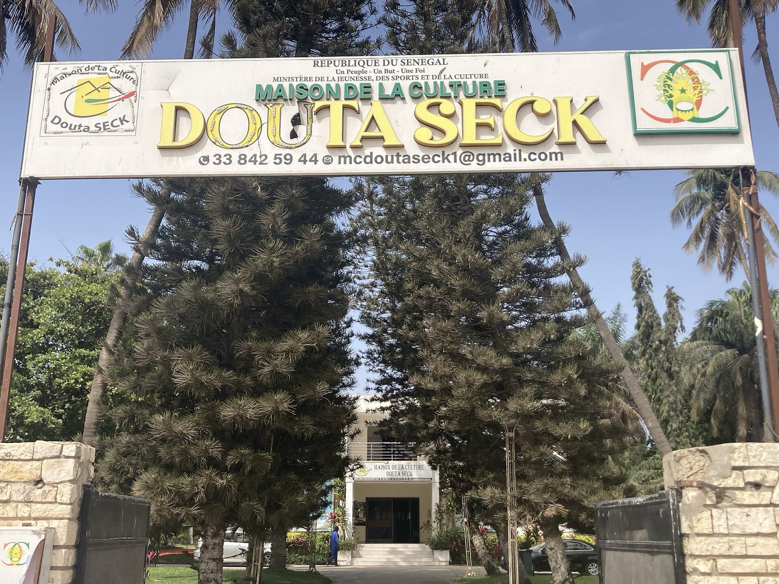 Entrada de la Maison de la Culture Douta Seck en Dakar, con su arco de bienvenida entre palmeras y muros de piedra.
